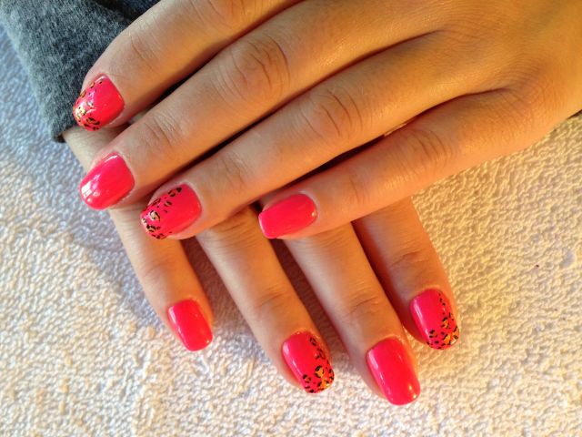 Coral pink gel manicure with leopard-print accent nails