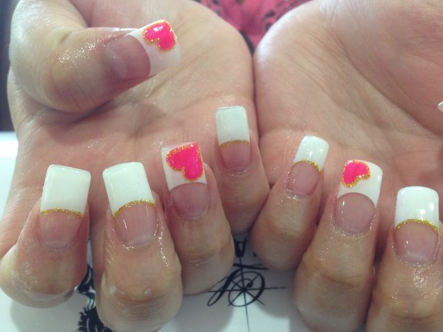 White French tips with gold glitter smile lines and hot pink hearts