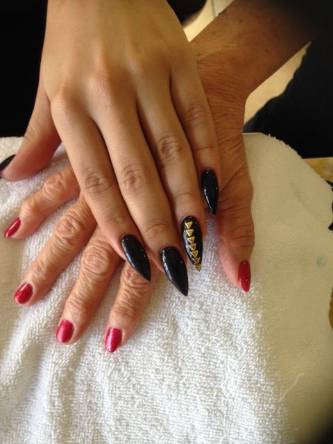 Black stiletto nails with a gold studded accent nail
