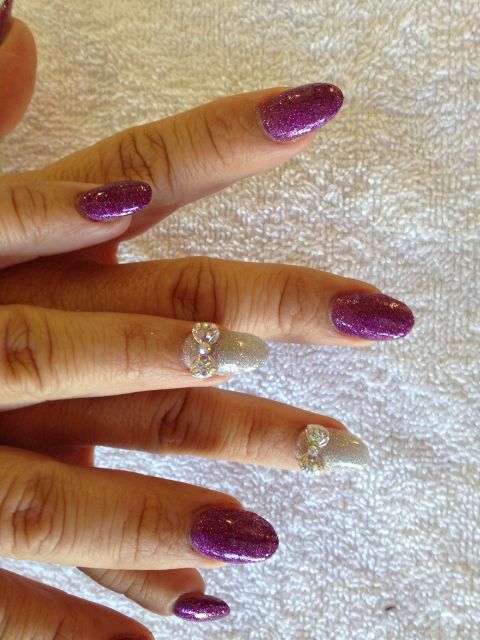 Purple glitter almond nails with silver glitter and rhinestone bow accents